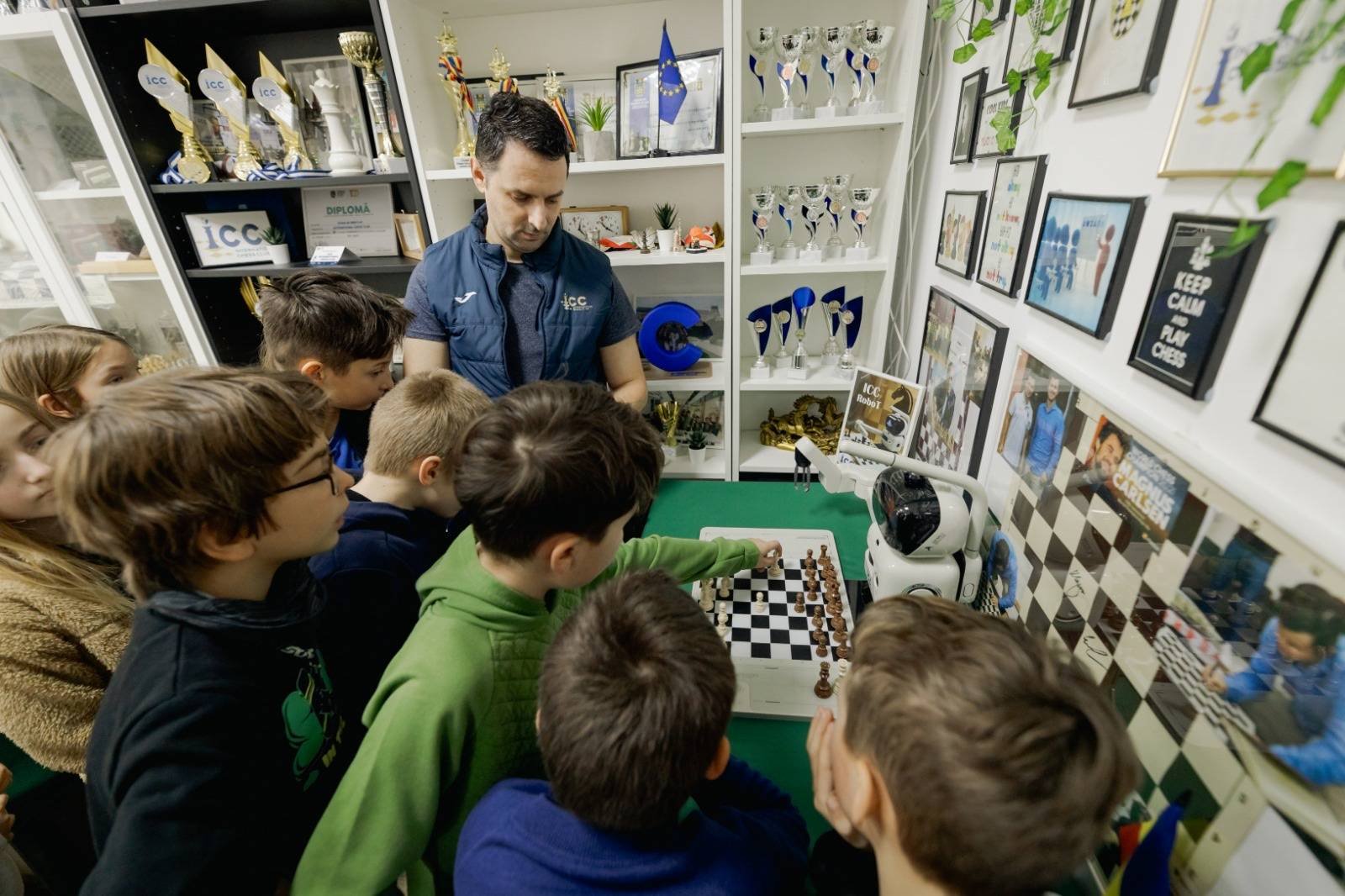 Copii la antrenamentul de șah de la International Chess Club Iași, împreună cu antrenorul și robotul ICC