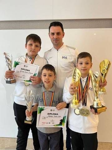 Antrenorul ICC alături de trei sportivi ai clubului cu diplome, cupe și medalii